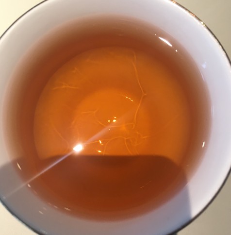 Looking down into a tea cup. A strong light is reflected at about 8 o'clock on the surface.  Lines of light on the bottom of the cup indicate convection zones.
