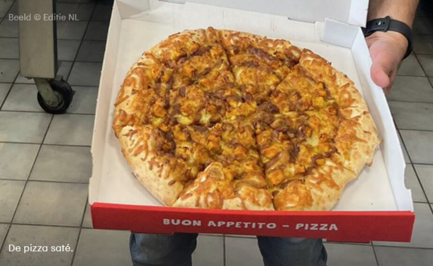 Een foto van de pizza saté in een pizzadoos. Het lijkt alsof een hond met diarree op een pizza margherita heeft gekakt.