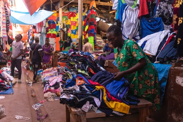 A woman selling secondhand clothes arranges several items at her stall while waiting for costumers in Owino, Kampala's largest secondhand clothes market. [Badru Katumba/AFP]