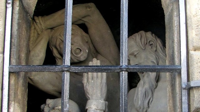Statues of people in a jail cell.