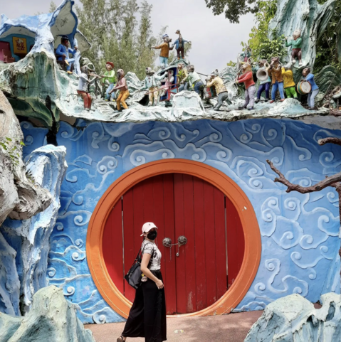 Woman with black backpack in front of red door