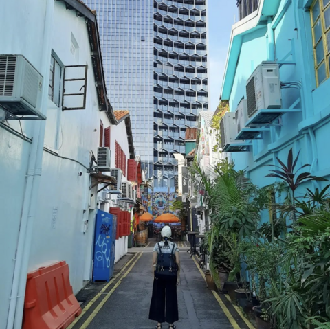 Woman with black backpack in a small alleyway looking up at buildings
