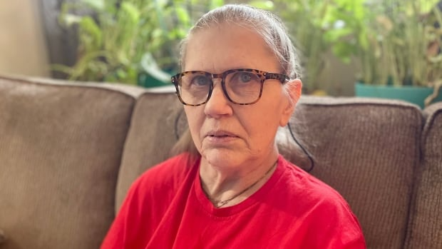 A woman sitting on a sofa in a red t-shirt.