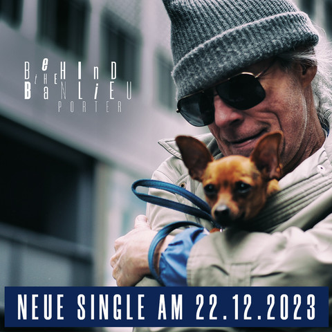 Alter Mann mit Hund auf dem Arm grinst.