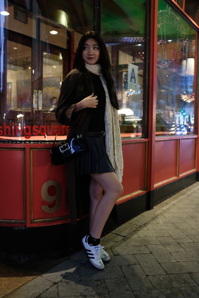 Girl standing in front of storefront windows at night