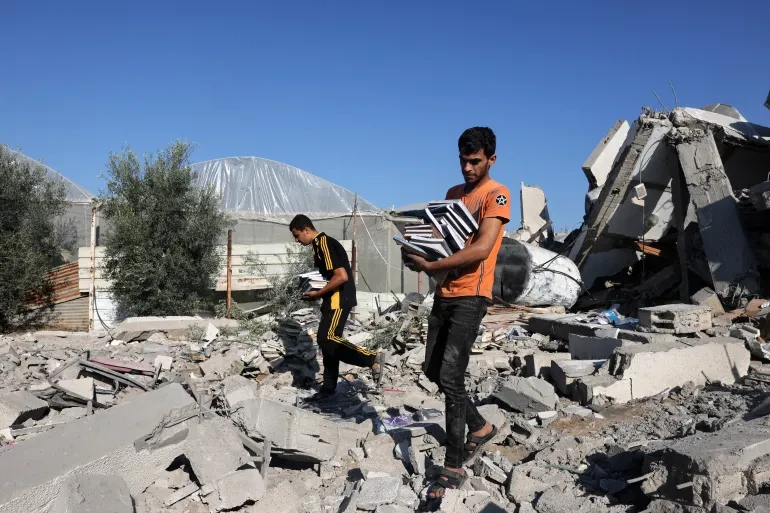 Palestinians collect books from the rubble of a cultural centre following an Israeli strike in Rafah in southern Gaza on November 18, 2023 [Mohammed Abed/AFP]