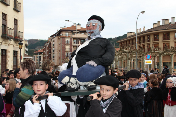 Photo of children varying an effigy of Olentzero through the streets of a Basque city as part of a holiday celebration