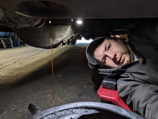 I'm laying on a creeper under a bus. A drain pan is in front of me with a stream of transmission fluid running into it.