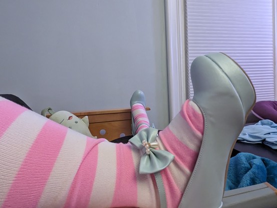 feet in pink striped socks and light blue high heels with a bow accent on the buckle