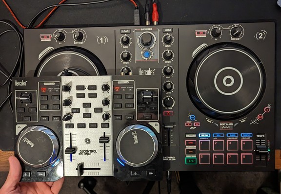 Big beautiful DJ controller in the background
Tiny controller held in front of it. 
The tiny one is a quarter of the size of the new one.