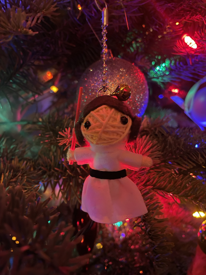 Close up shot of a decorated Christmas tree with multi coloured lights. Decoration of a felted Princess Leia brandishing a red lightsaber in the foreground.