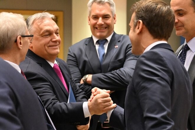 Le premier ministre hongrois Viktor Orbán et le président français Emmanuel Macron se serrent la main avant une table ronde du Conseil européen au siège européen à Bruxelles, le 14 décembre 2023. © Photo Miguel Medina / AFP