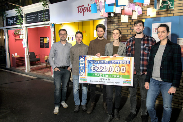 Team von sechs Menschen vor einen Marktstand.