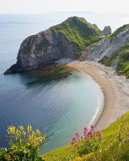 A beautiful view of the green mountains and hills near the sea in Durdle Door, Wareham, UK