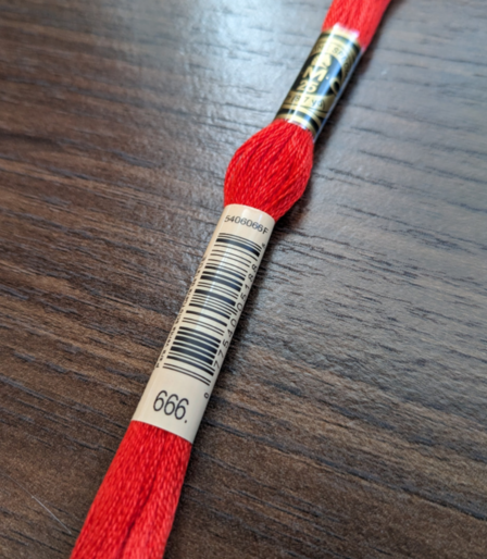 Red DMC-brand cross stitch thread with the label identifying the color code as 666.
