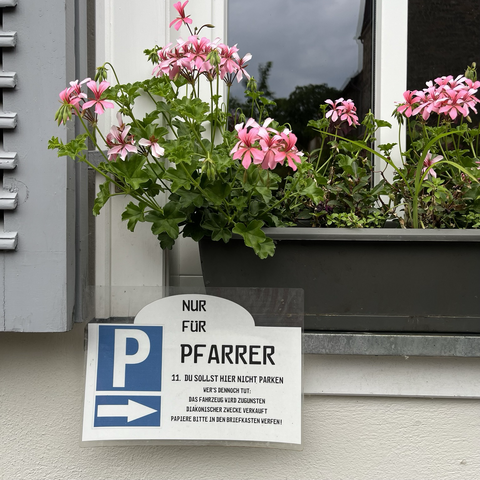 The picture shows a sign that says “0nly for vicar - 11th commandment you must not park here. If you do your car will be sold in aid of good causes. Please leave car papers in letterbox.”