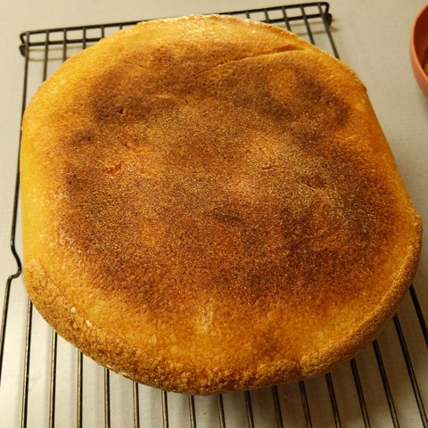The bottom of the bread, it is dark brown in the center and lighter towards the edges.
