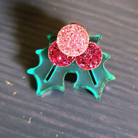 A single acrylic earring, three glitter holly fruits & two shiny holly leaves