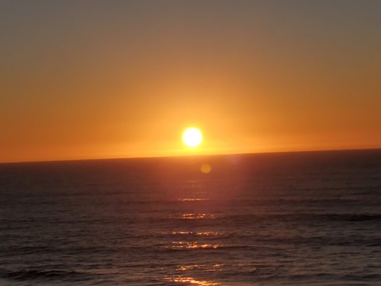 Old Sol looking very shiny indeed.  Orange glow of sunset contrasting with tranquil dark blue ocean below.