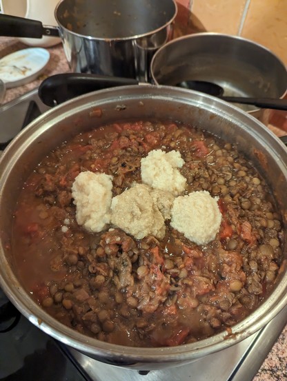 A pan with a lot of lentils, onions, tomatos and garlic