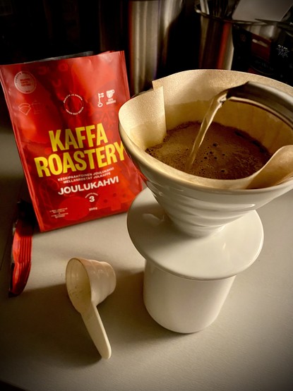 A red bag of coffee in the background as I do a pour over into a white mug using a Hario V60 ceramic dropper and 02 unbleached filter.

Text from the bag in Finnish;

KAFFA ROASTERY
KESKIPAANTOINEN JOULUKANY
MELLANROSTAY SULKARFE
JOULUKAHVI