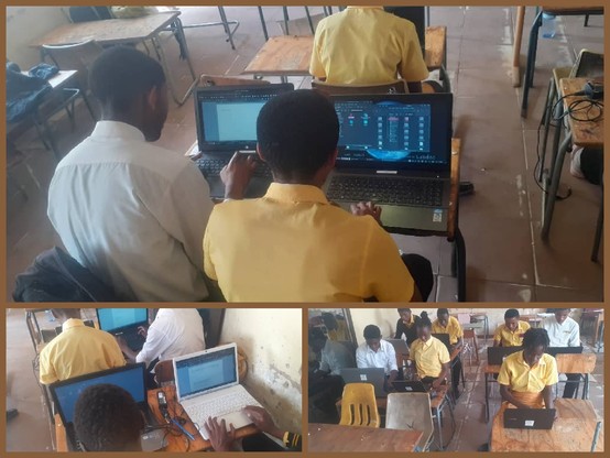 In einem Klassenraum sitzen an Schultischen aus Rohrgestänge und einer Holzplatte ca. 10 junge Menschen vor Laptops. Auf den Monitoren sieht man verschiedene Programme wie LibreOffice Writer Textverarbeitung, Dateimanager u.a. in die sich die Teilnehmer einarbeiten.