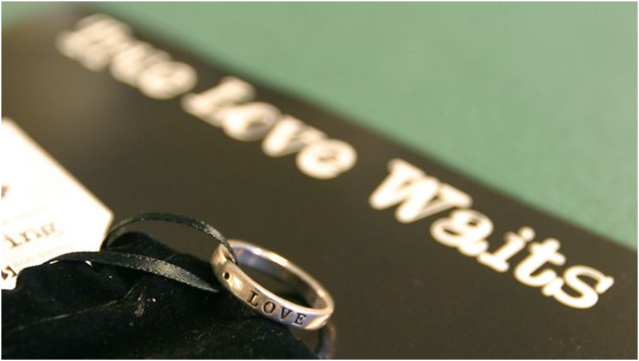 Auf dem Foto ist der Schriftzug True Love Waits zu sehen und direkt davor liegt ein Ring mit der Aufschrift Love.