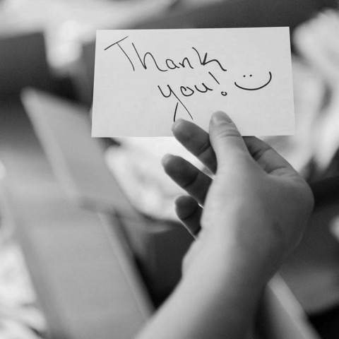 Someone holding a thank you note with a smiley face.