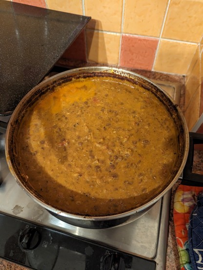 A steel pot with a light brown lentil stew dish in it. 