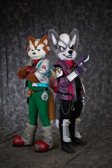 Fox McCloud and Wolf O'Donnell fursuits standing back to back.
