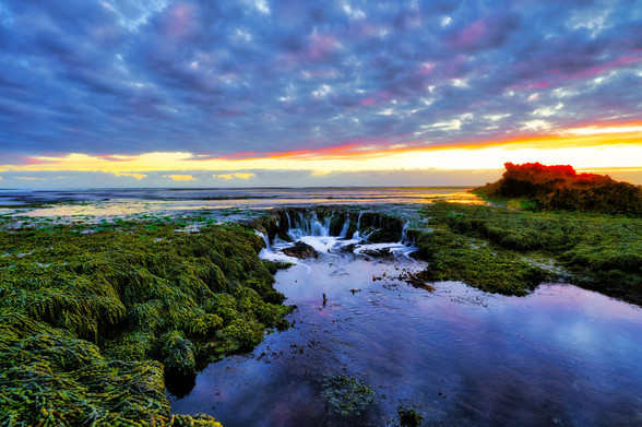 An exposed sea shelf dropping a mini waterfalls in rye Mornington Peninsula Melbourne Australia 

Sunset and fish scale sky 