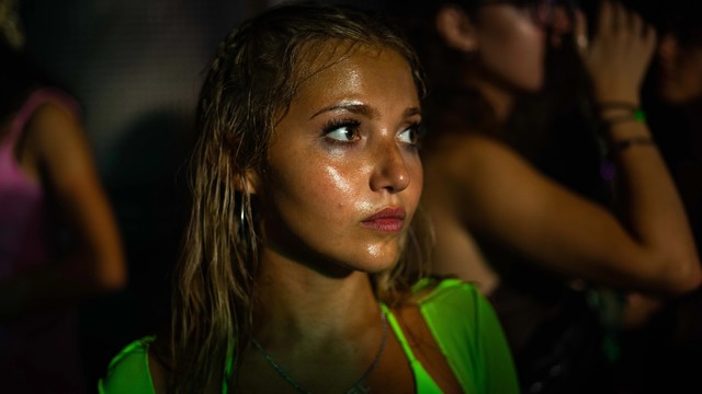 Filmszene mit der vom Tanzen nassgeschwitzten Mia McKenna-Bruce mit einem neongrünen Oberteil