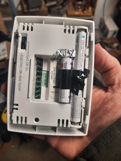Honeywell thermostat with an extra AAA cell inserted using Aluminum duct tape as a conductor and electrical tape as an insulator and to hold down the extra battery.