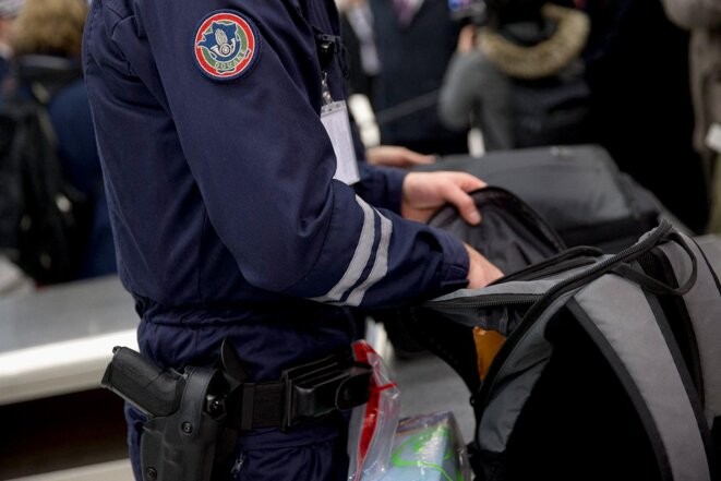 Contrôle de bagage par un douanier à l'aéroport Roissy-Charles-de-Gaulle. © Photo Kenzo Tribouillard / AFP