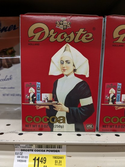 Photo of a box of "Droste" brand powdered hot chocolate on a grocery store shelf. The box has a picture of a nun (?), who is holding a tray with a smaller box of Droste and a mug. The small box of Droste within the picture has an even smaller picture of the nun holding yet another tray with a tinier box of Droste and a mug. Presumably, the image within the image continues on ad infinitum.