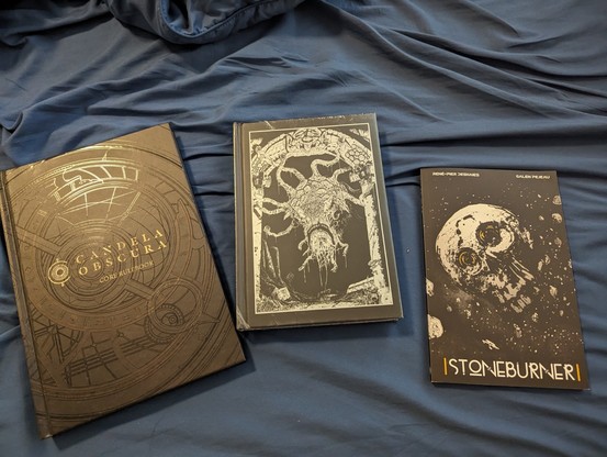 Three TTRPG rule books. Candela Obscura, Shadow dark, and Stoneburner.