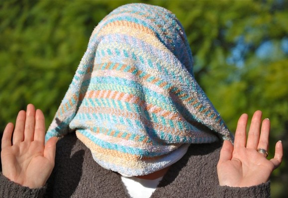 Mrs Crawford pleading that no more photographs be taken. She has her hands up with a towel over her head.