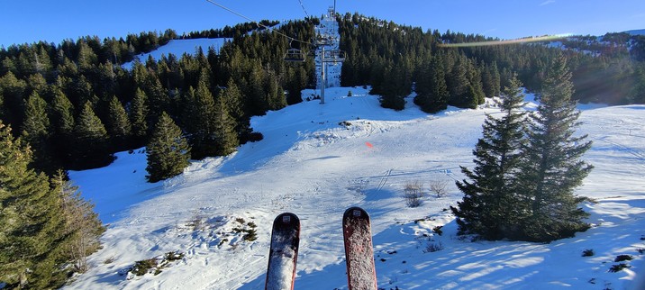 Photo de mes skis, pendant ma montée en téléski sur l'une des pistes de Lélex. On y voit de la neige, des sapins et le téléski avec un peu de soleil ... Une belle photo de paysage, prise depuis mon siège téléski 