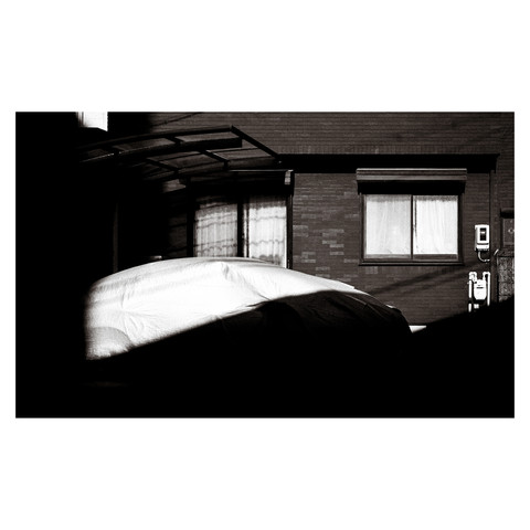 A streamlined car covered for protection, sits beneath a curving roofline with transparent sections, creating a harmonious blend of form and function.