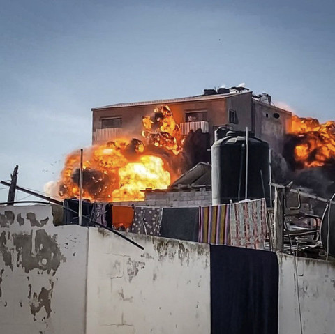 2: The same building with fire exploding out of its windows. The outside of the building still appears intact but the bomb is blowing it out from the inside. 