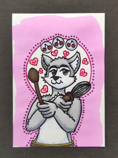Une carte représentant Féliko, personnage félis de Hellypse, prenant l'apparance d'un chat anthro blanc et gris, avec un fouet et une cuillère, des coeurs autour de la tête et trois cerises au dessus, sur fond rose.