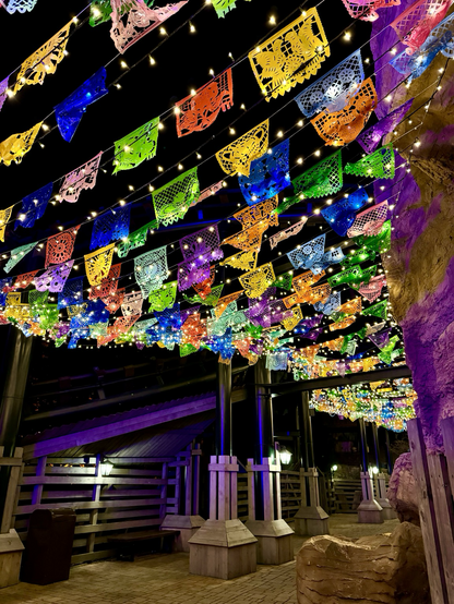Photo of coloured paper flags above an empty pathway at night. Near Colorado Adventure at Phantasialand. 