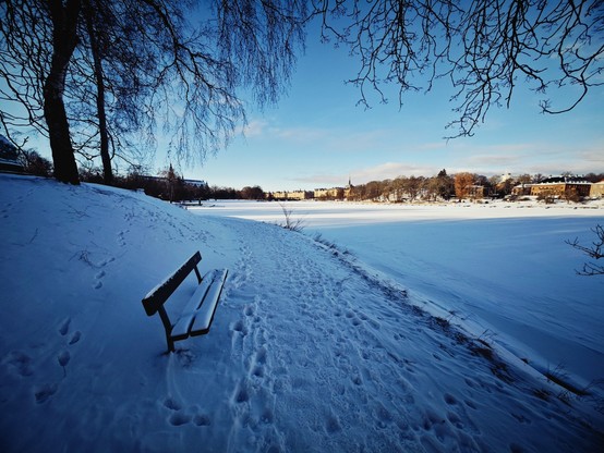 park bench along snowy trail and frozen waterway