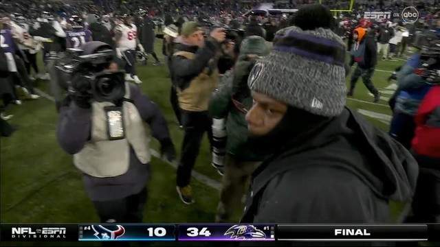 Post-game scene at a football event with people and photographers on the field, scoreboard showing a final score of 34 to 10.