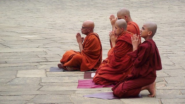 Buddhist monastics with hands in anjali. Possibly facing a shrine or stupa.