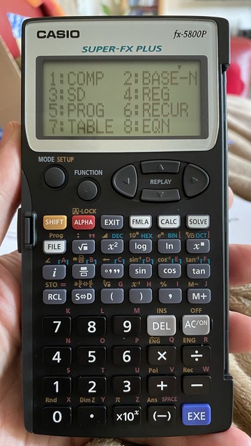 A Casio fx-5800P scientific calculator held in a person's hand.