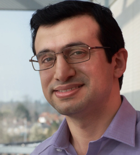 Dr. Danesh Tarapore, wearing a mauve shirt and glasses, smiling.