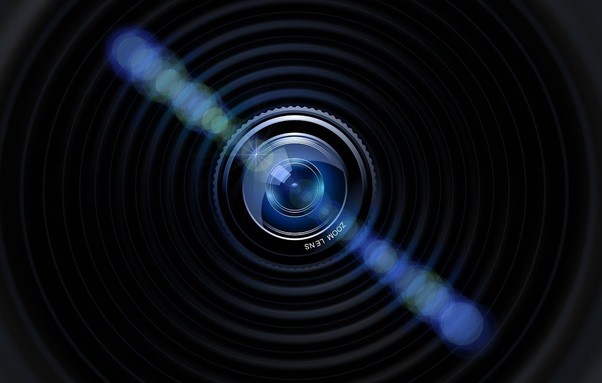 The image shows a camera lens with light reflections 