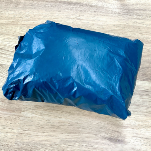 A package in blue plastic, shown on a light wooden background.