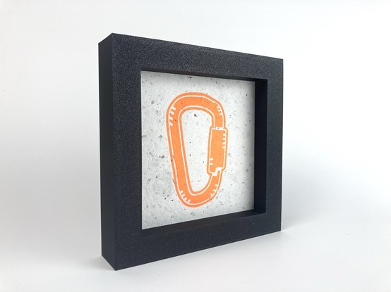 A framed print of an orange carabiner.